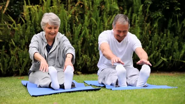 Mature couple stretching on gym mats — Stock Video