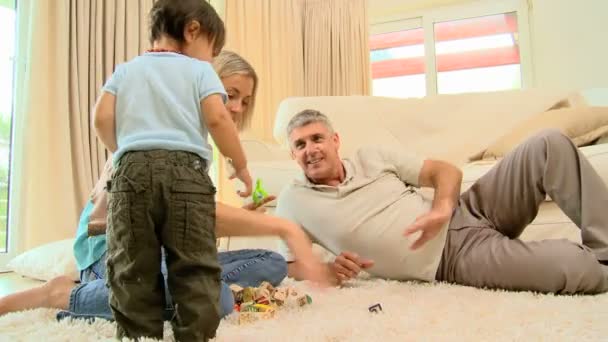 Young woman on carpet blowing bubbles for baby and husband — Stock Video