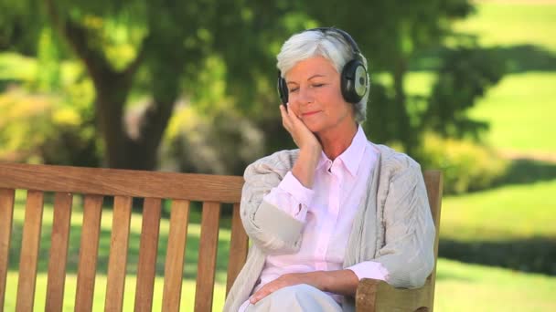 Femme mûre écouter de la musique à l'extérieur — Video