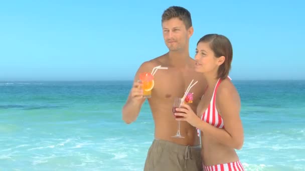 Pareja bebiendo cócteles en una playa — Vídeo de stock