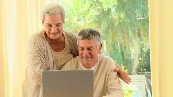 Зрелая пара улыбается о чем-то на ноутбуке — стоковое видео
