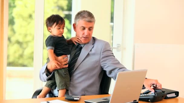 Mann macht Büroarbeit, während er Baby hält — Stockvideo