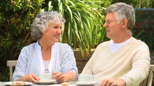 Зрелая пара пьет кофе в саду — стоковое видео
