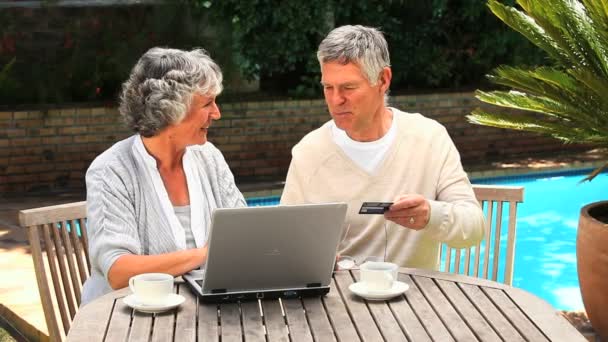 Casal aposentado usando um cartão de crédito para comprar online — Vídeo de Stock