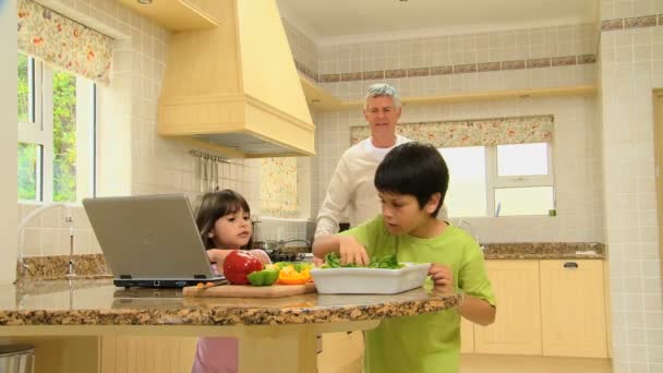 Niños recogiendo ingredientes para una receta que tienen en un portátil — Vídeo de stock