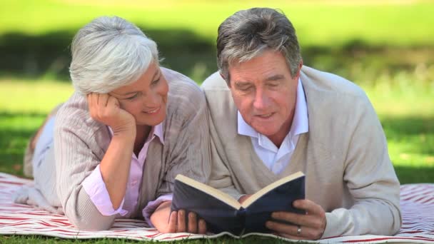 Mature couple reading a book outside — Stock Video