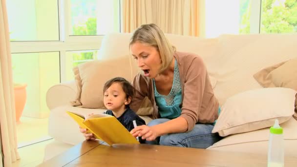 Ung kvinna visar sin baby en barnens bok — Stockvideo