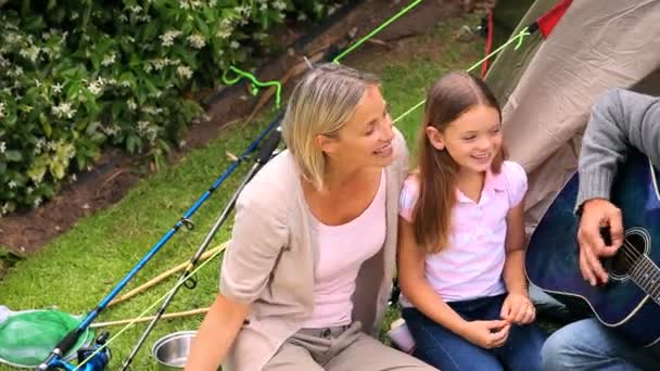 Father playing guitar with wife and children singing in garden — Stock Video