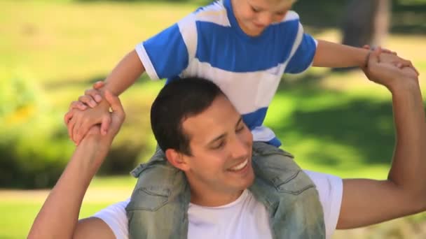 Genç çocuk babasının omuzlarında oynarken — Stok video