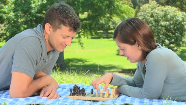 Jeune couple jouant aux échecs sur l'herbe — Video
