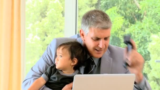 Businessman working at the desk with baby — Stock Video