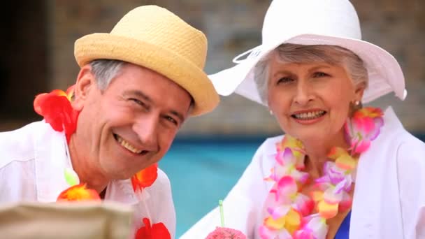 Älteres Paar mit Hüten und Girlanden trinkt Cocktails — Stockvideo