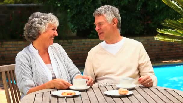 Ώριμο ζευγάρι που έχοντας απογευματινό τσάι από μια πισίνα — Αρχείο Βίντεο