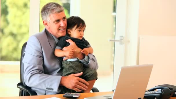 Man in office coping with baby and laptop — Stock Video