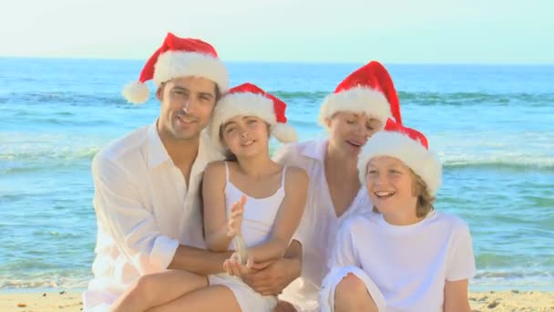 Família feliz usando chapéus de Natal em uma praia — Vídeo de Stock