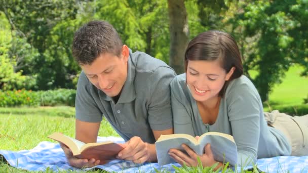 Smiling young couple reading outdoors — Stock Video