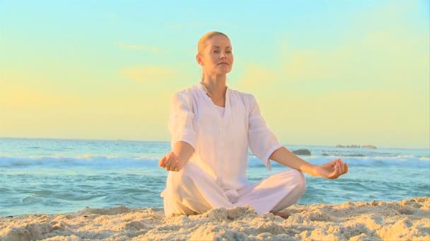 Vrouw in wit doet yoga op het strand — Stockvideo