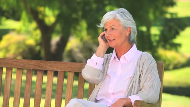 Madura mujer llamando en un banco público — Vídeos de Stock