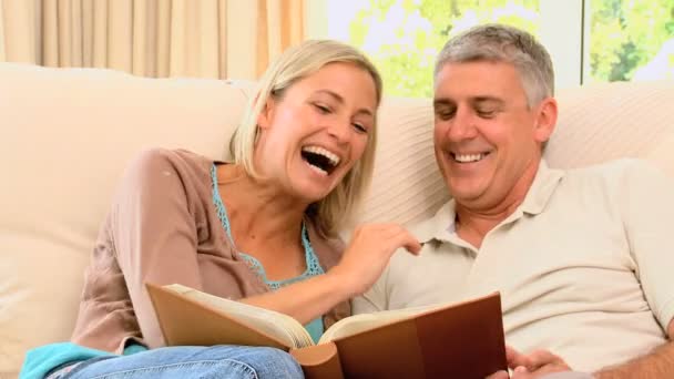 Couple looking at an album and laughing — Stock Video