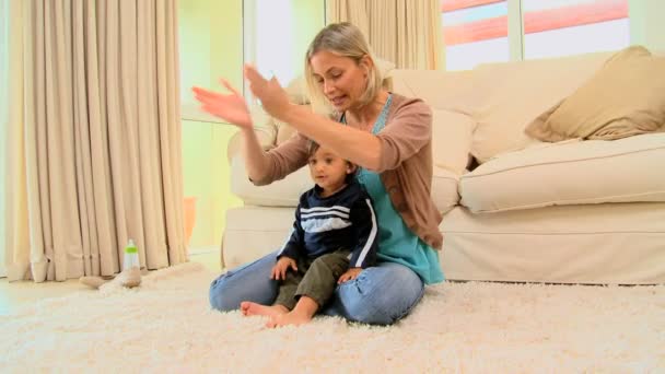 Молодая мама играет со своим ребенком на ковре — стоковое видео