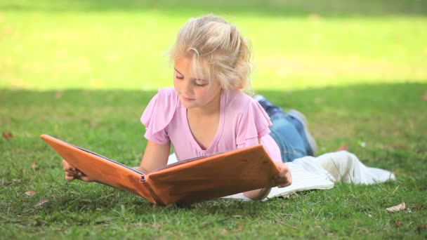 Young girl reading a book outdoors — Stock Video