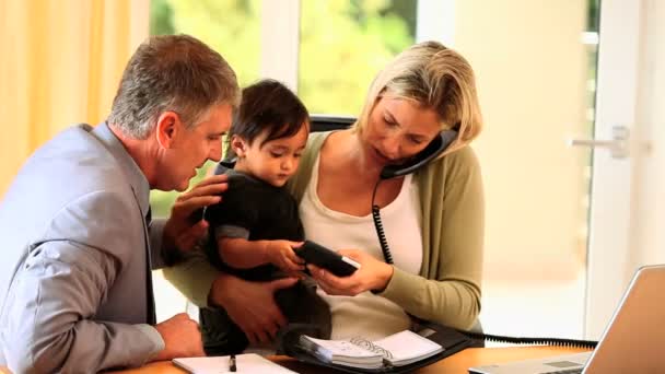 Parents trying to work at a desk with baby — Stock Video