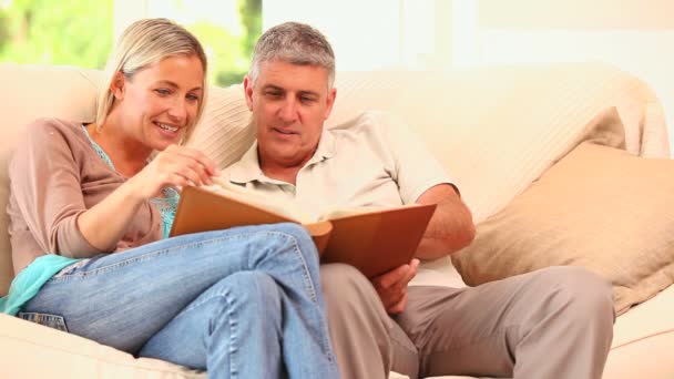 Atractiva pareja mirando un álbum — Vídeos de Stock