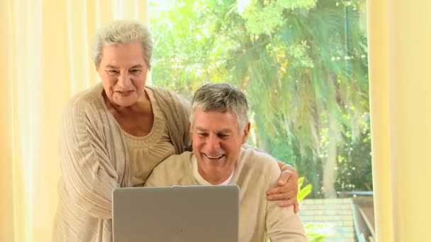 Пожилая пара смеется над чем-то на ноутбуке — стоковое видео