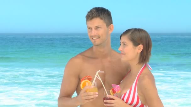 Pareja posando con cócteles en una playa — Vídeo de stock