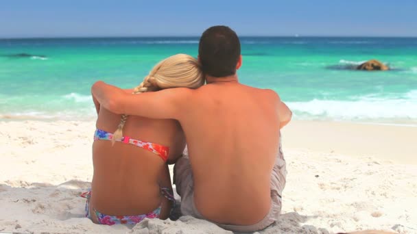 Couple assis sur le sable regardant la mer — Video