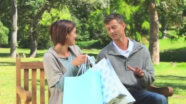 Jovem casal sentado em um banco com suas compras — Vídeo de Stock