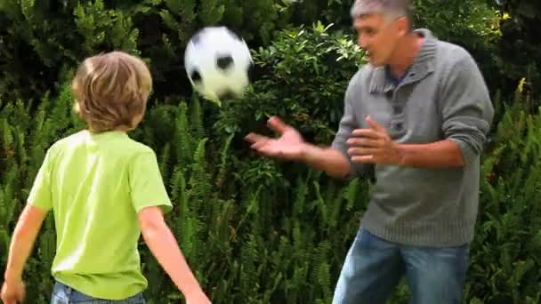 Père et fils jouant avec le football dans le jardin — Video
