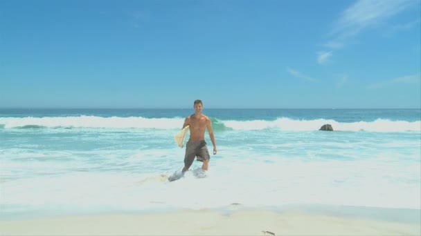 Mann mit Surfbrett kommt aus dem Wasser — Stockvideo