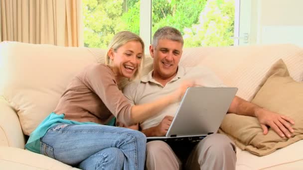 Casal no sofá desfrutando de algo no laptop — Vídeo de Stock