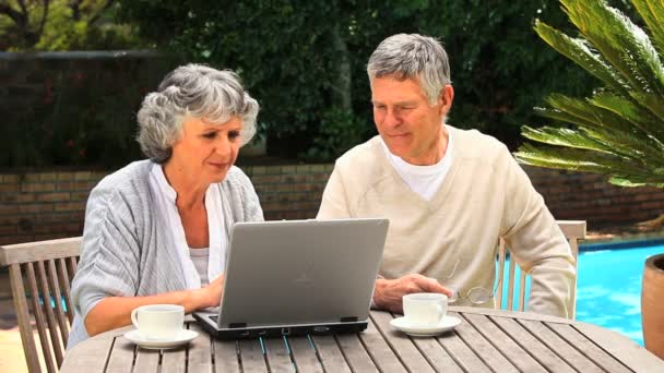 Mature couple working on a laptop in the garden — Stock Video