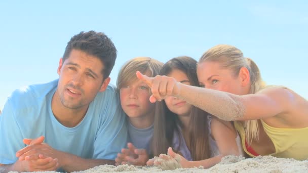Милая семья наблюдает за кем-то на пляже — стоковое видео