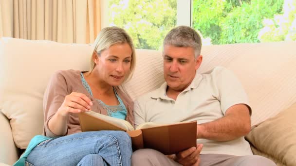 Couple on sofa looking through an album — Stock Video