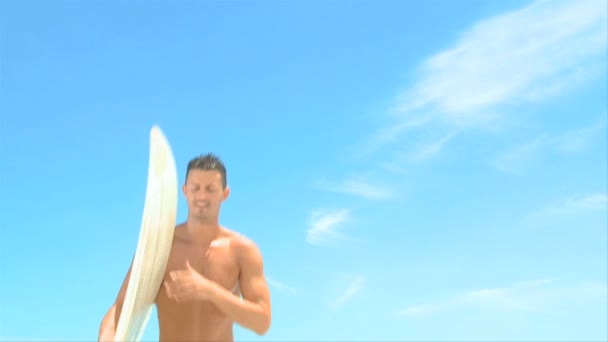 Dobře stavěný muž dostat z vody po surfování — Stock video