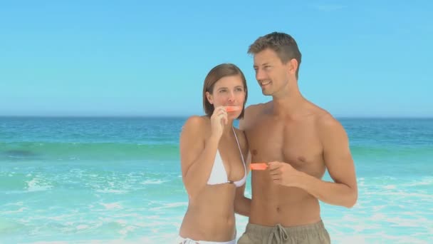 Couple eating water ices on a beach — Stock Video