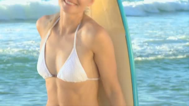 Блондинка позирует со своей доской для серфинга — стоковое видео