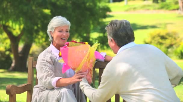 Älterer Mann schenkt seiner Frau einen Blumenstrauß — Stockvideo