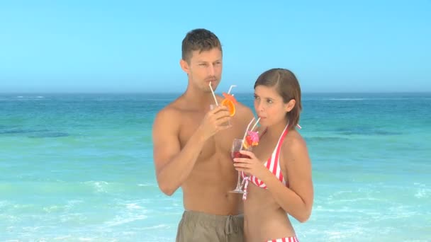Happy couple posing drinking cocktails in front of the sea — Stock Video
