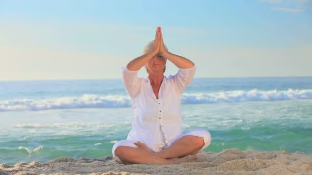 Mujer haciendo yoga en una playa — Vídeo de stock