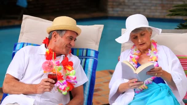 Casal maduro com guirlandas conversando em cadeiras de praia — Vídeo de Stock