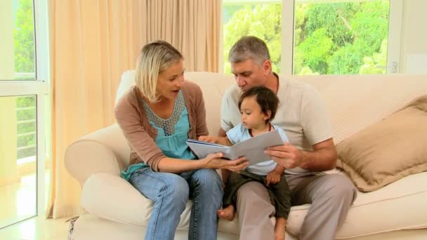 Padres enseñando a su bebé un libro ilustrado — Vídeos de Stock