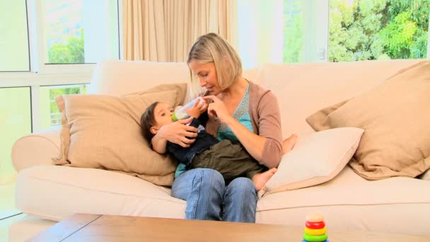 Joven madre biberón alimentando a su bebé y riendo — Vídeo de stock