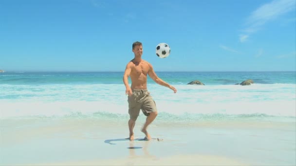 Adam bir plajda bir futbol topu ile — Stok video