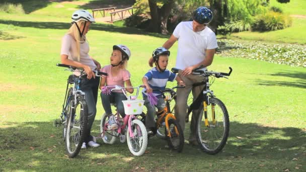 Pareja joven con sus dos hijos listos para ir en bicicleta — Vídeo de stock