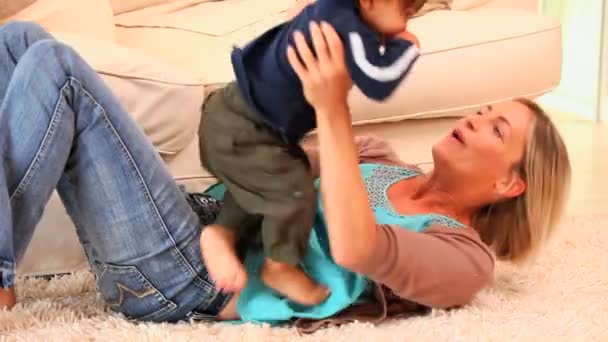 Mère allongée sur un tapis jouant avec son bébé — Video