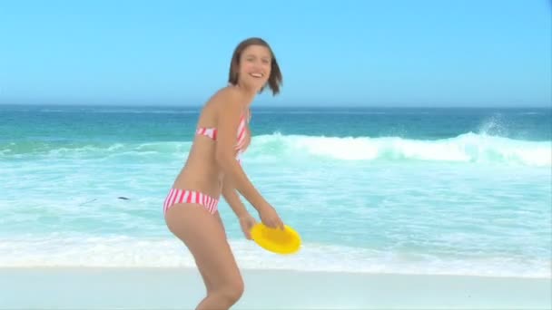 Woman in stripped swim suit playing frisbee — Stock Video